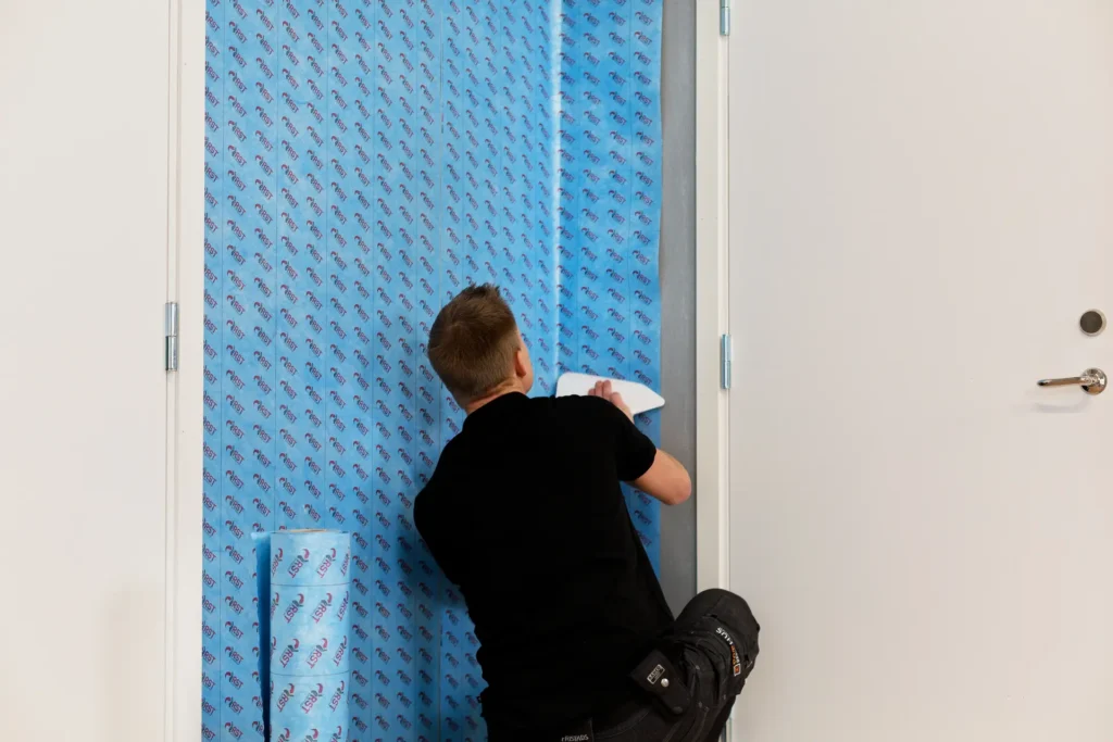 Person monterar radontapet på vägg