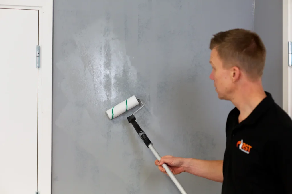 Man rollar på vägg för att sätta upp radontapet