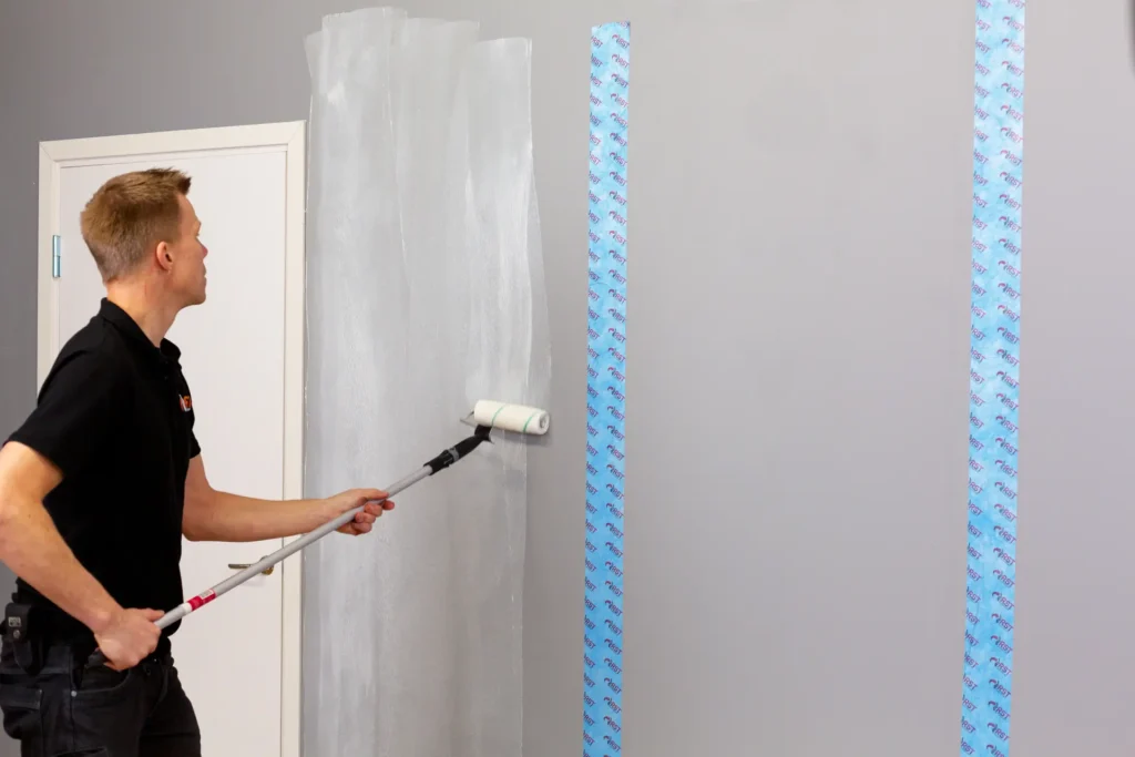 Man rollar på vägg för att sätta upp radontapet